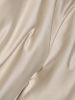 Cream-colored fabric with soft folds and a smooth texture creates a gentle flow across the surface.