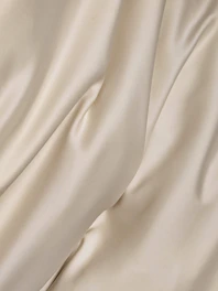 Soft organic cream-colored casual pants folded neatly with dusty blush accents.