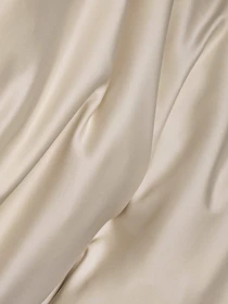 Soft folds of cream colored satin fabric with smooth highlights and deep shadows