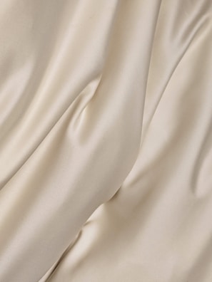 Cream-colored fabric with soft folds and a smooth texture creates a gentle flow across the surface.