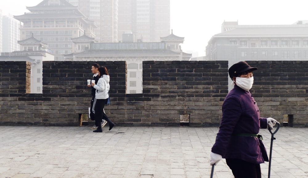 man in purple jacket and black pants standing beside woman in white long sleeve shirt