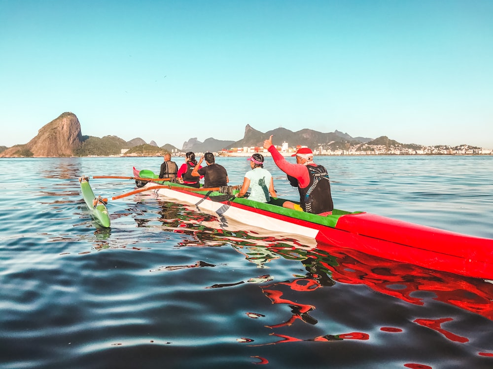 people riding red kayak on sea during daytime