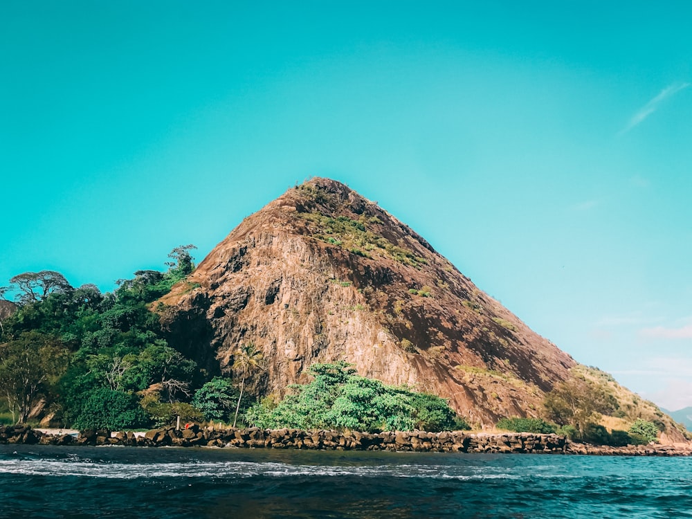 brown mountain near body of water during daytime