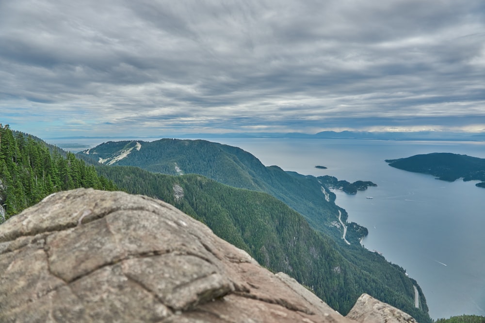 green mountains beside blue sea under white clouds and blue sky during daytime