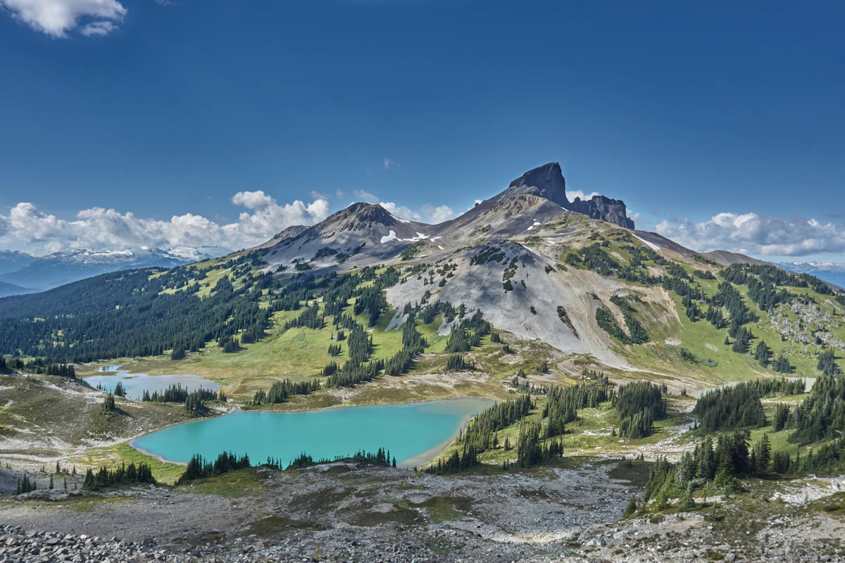 The Black Tusk above green alpine slopes and a turquoise lake