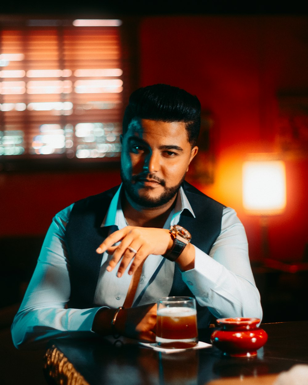 man in black vest and white dress shirt holding clear drinking glass