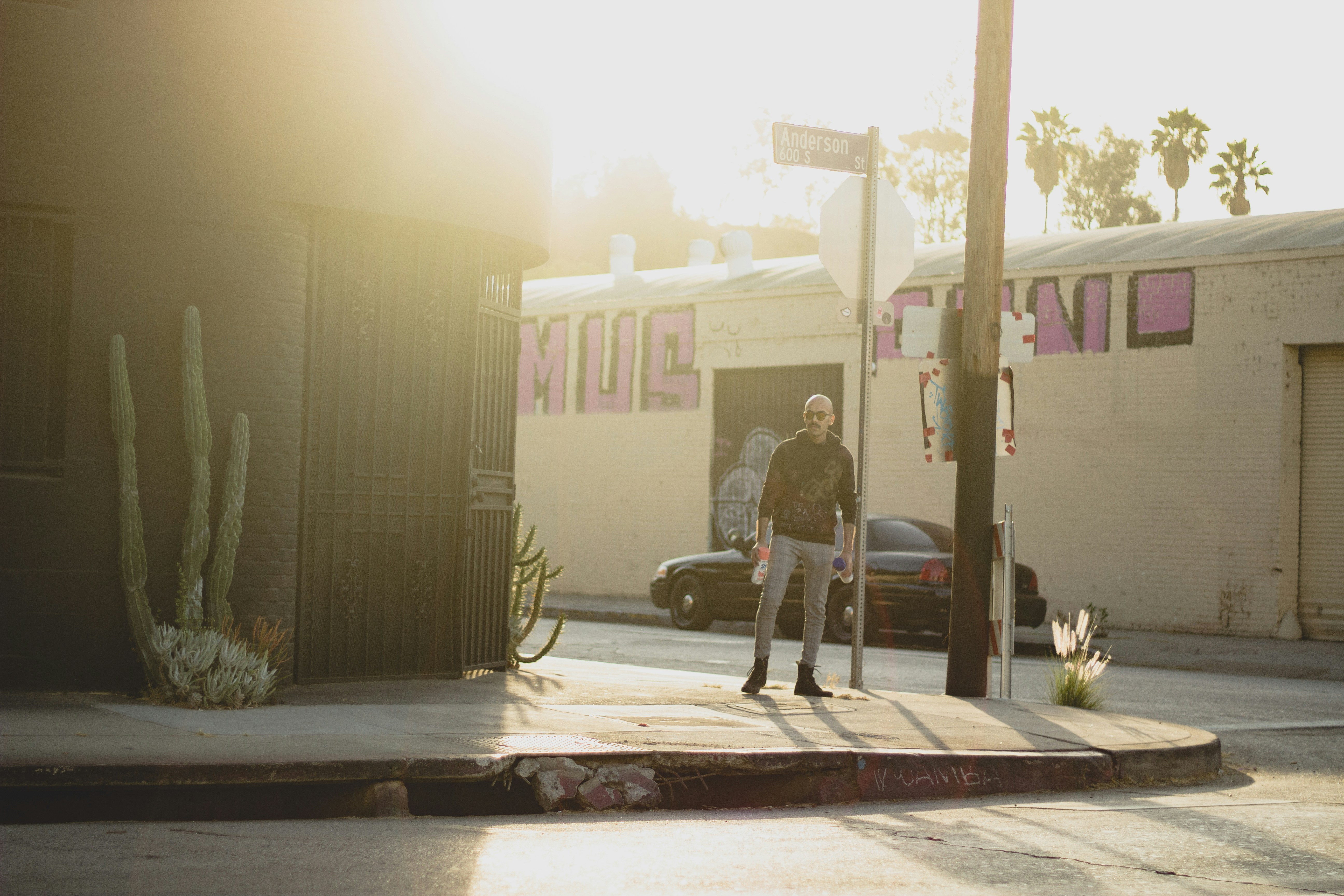 man in gray jacket and black pants standing beside brown building during daytime