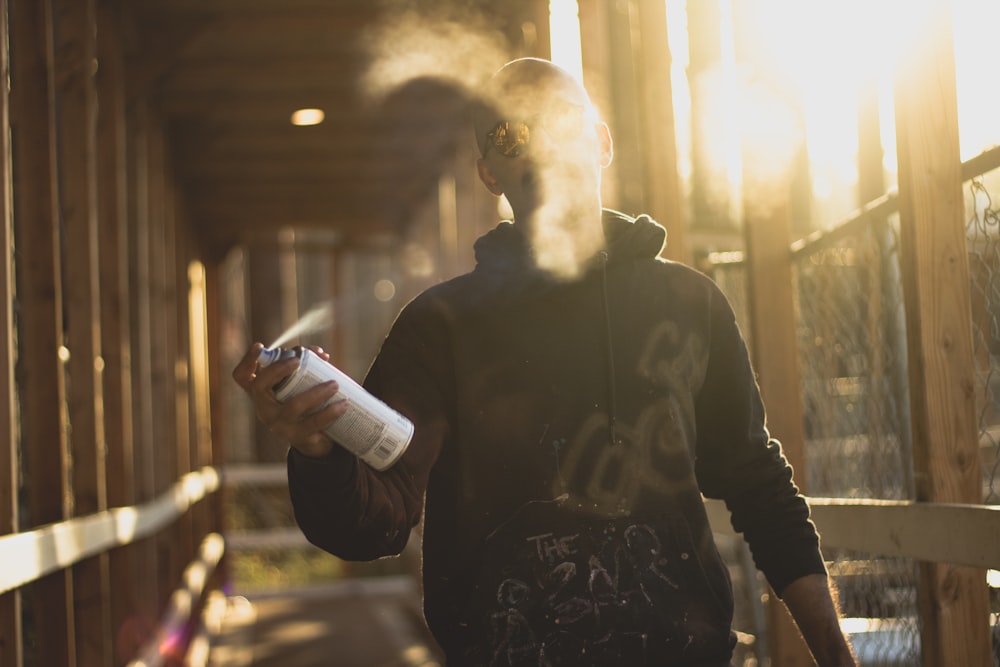 man in black jacket holding white can