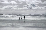 Cinematic shot of a family playing by the shore with waves gently rolling in.
