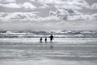 A family walking happily along a sunny beach during a cruise stop.