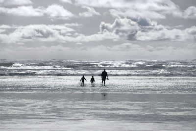 Cinematic shot of a family playing by the shore with waves gently rolling in.