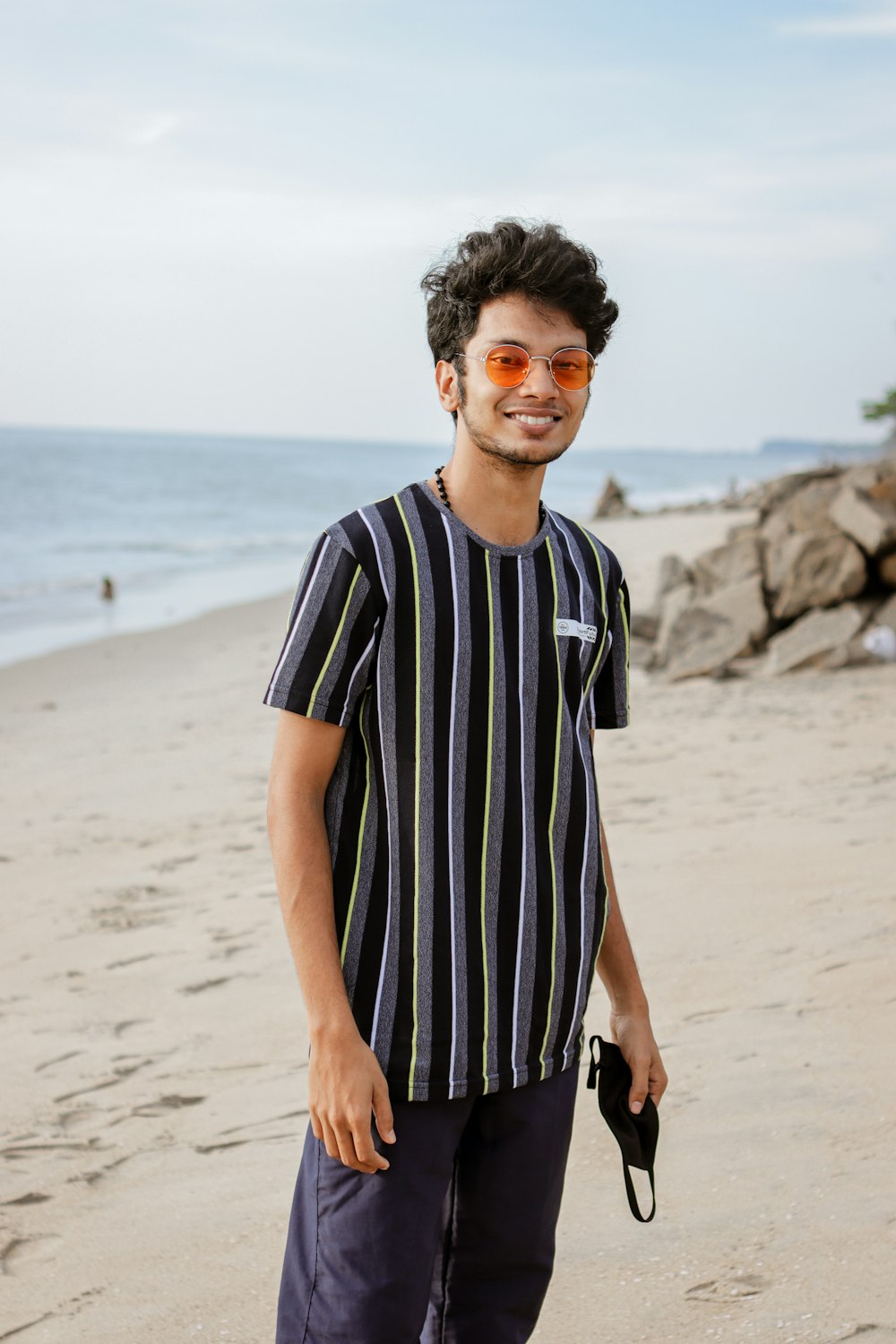man in black and white striped crew neck t-shirt standing on beach during daytime