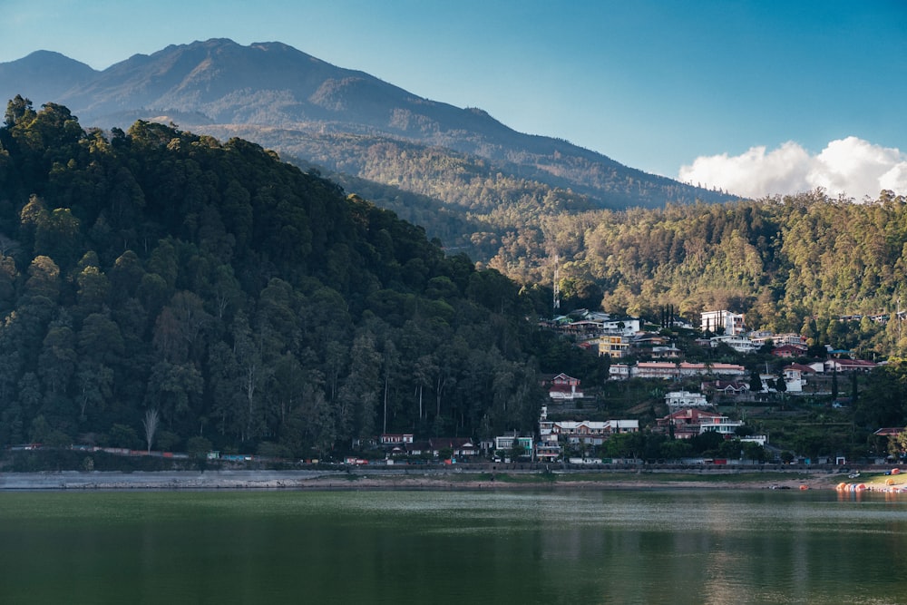 houses near body of water and mountain during daytime