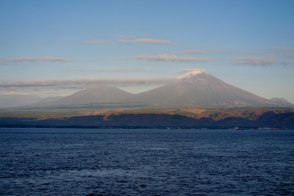 brown mountain near body of water during daytime