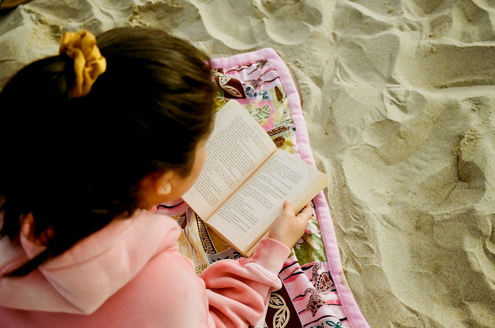 girl in pink hoodie reading book
