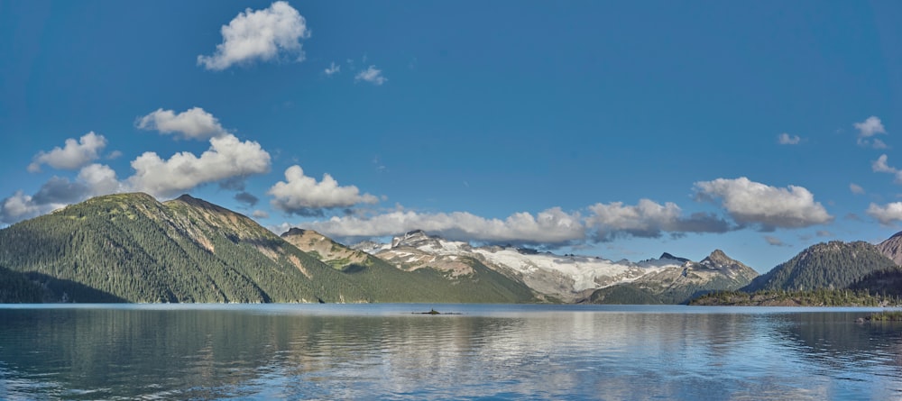 white and black mountains near body of water under blue sky during daytime