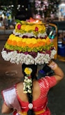 person holding white yellow and pink floral cake