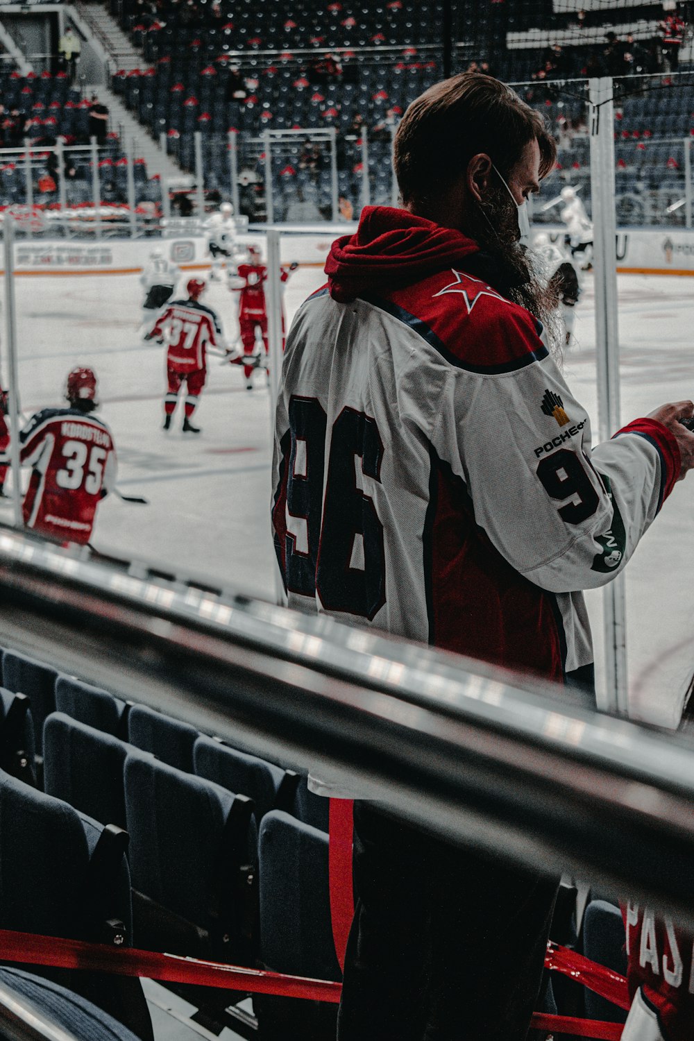 person in red and black jacket standing on ice hockey field