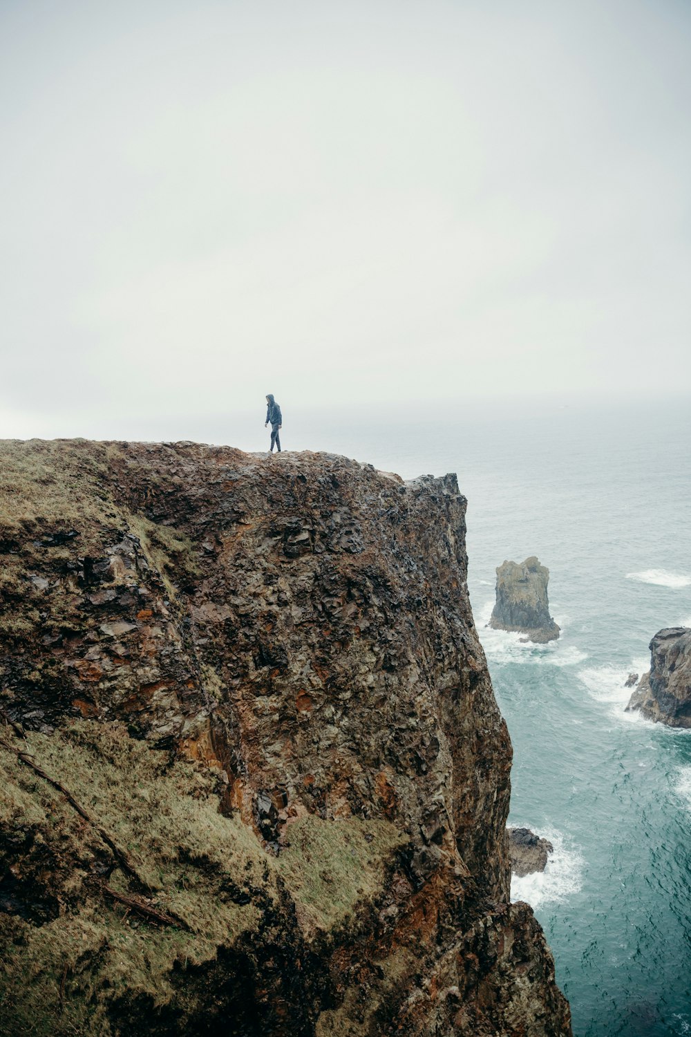 person standing on brown rock formation near body of water during daytime