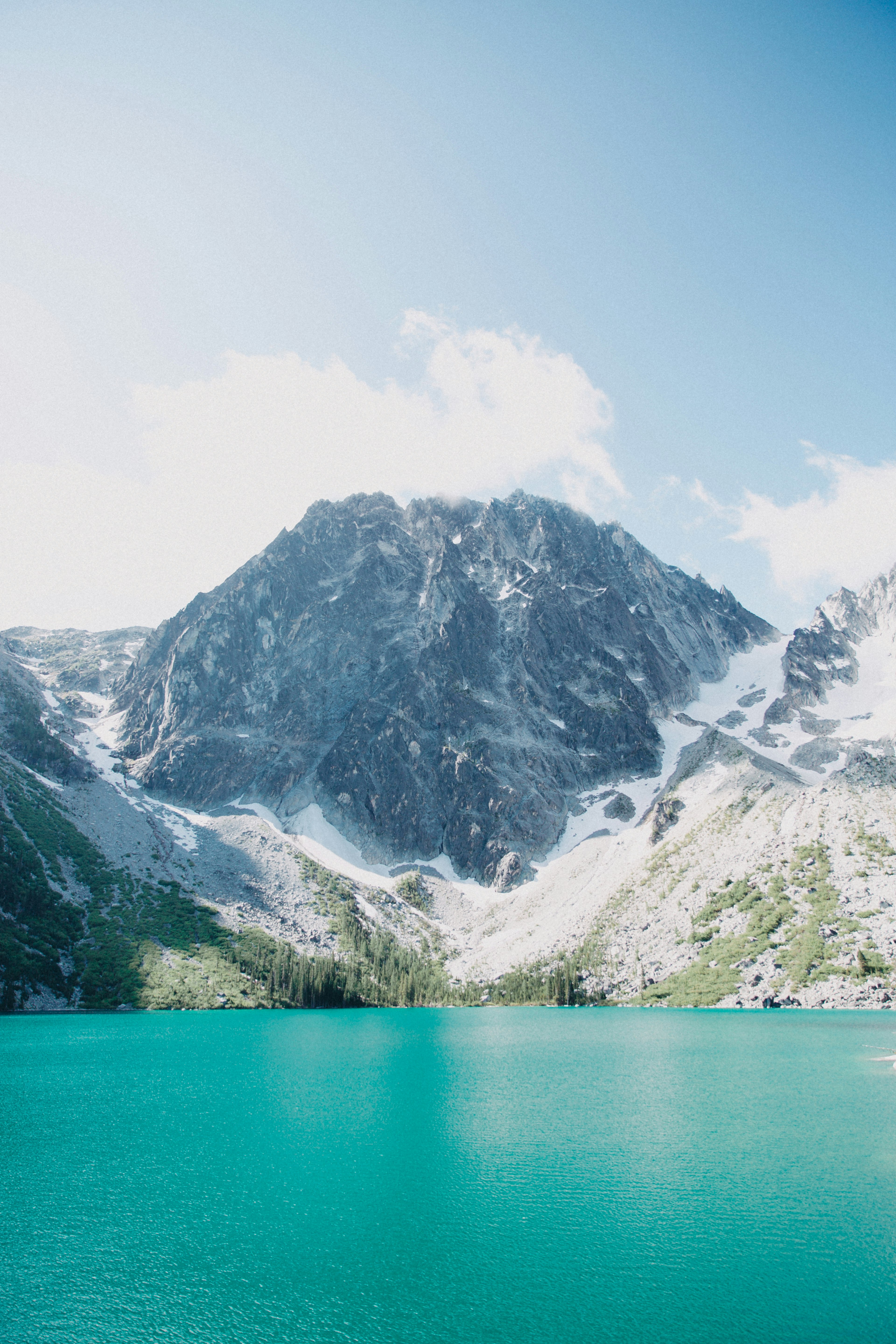 green and white mountains beside body of water during daytime