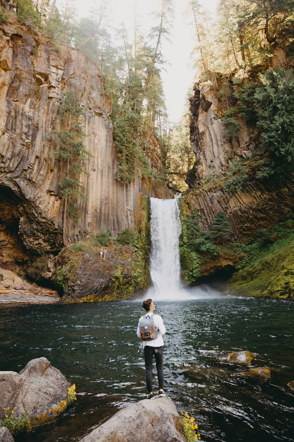 man in white shirt standing on river during daytime