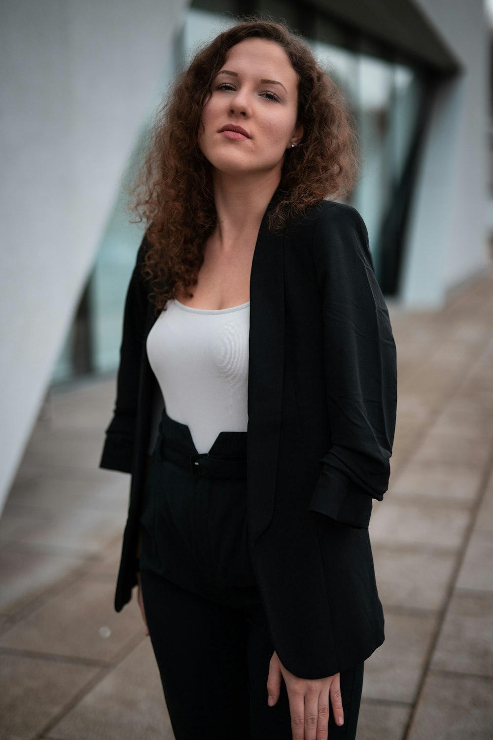 woman in black blazer standing on gray concrete floor