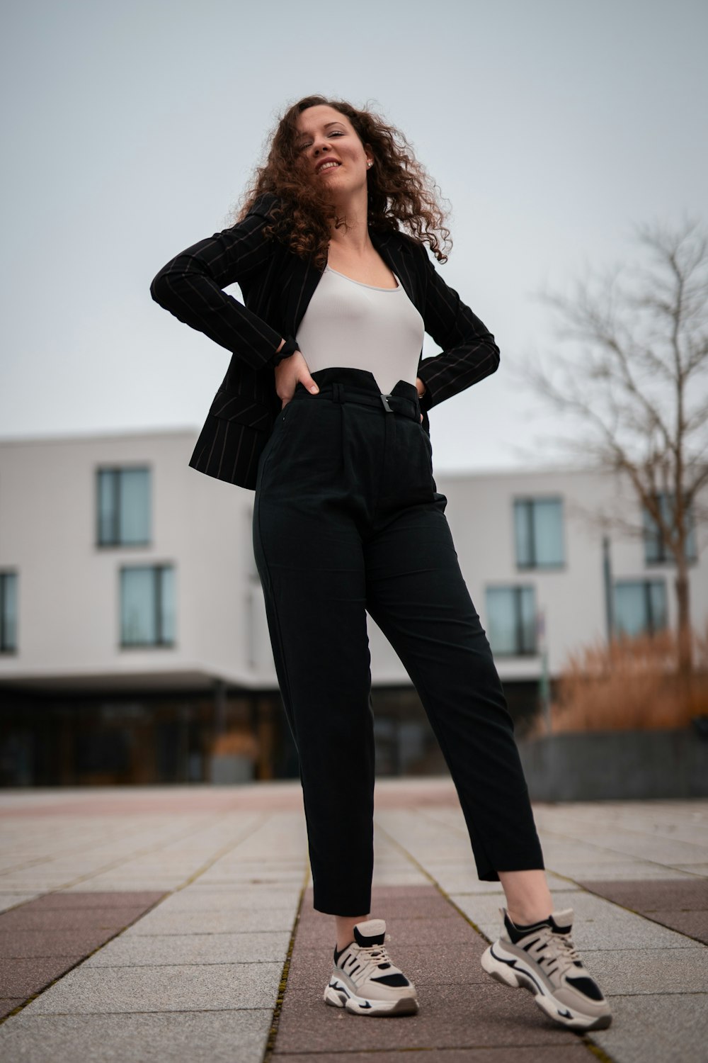 woman in black leather jacket and black pants standing on sidewalk during daytime