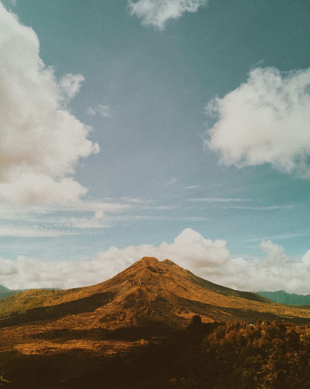 brown mountain under white clouds and blue sky during daytime