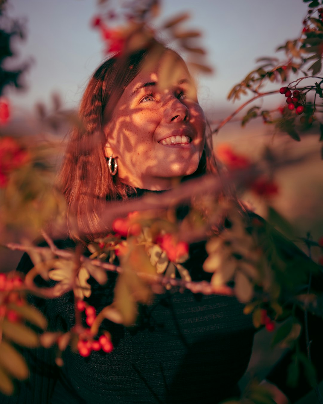 woman in black shirt standing near red flowers during daytime