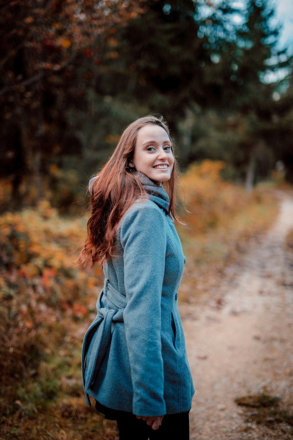 Femme en robe à manches longues bleue debout sur un chemin de terre marron pendant la journée