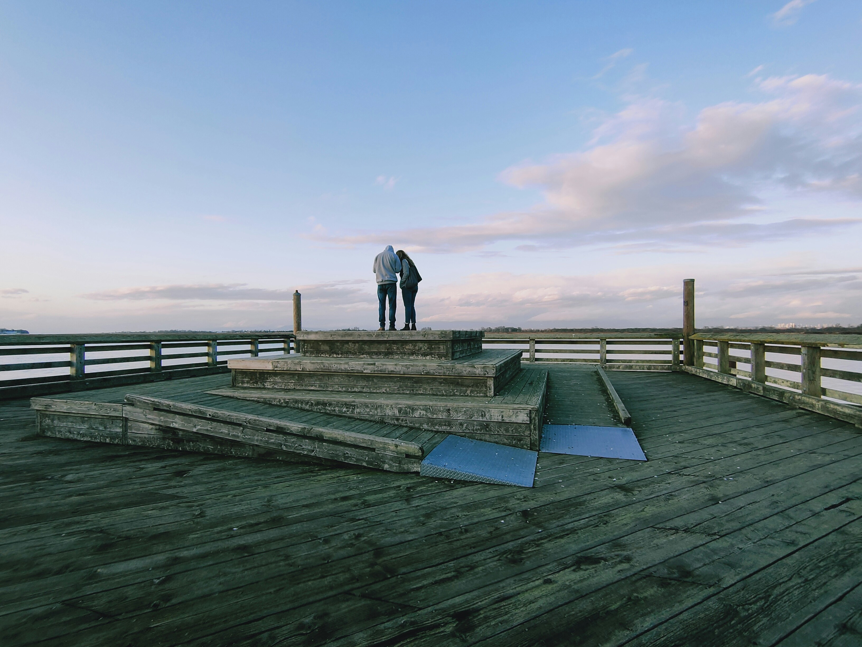man in black jacket and pants walking on wooden dock during daytime