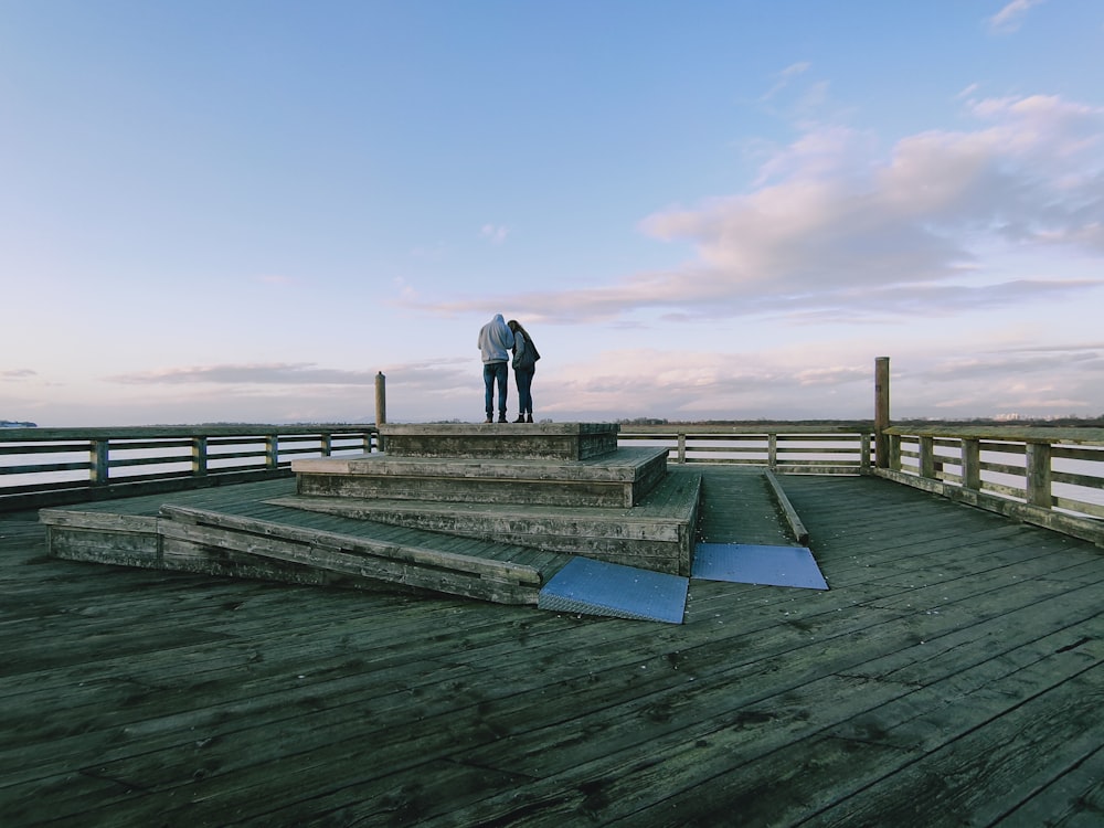 man in black jacket and pants walking on wooden dock during daytime
