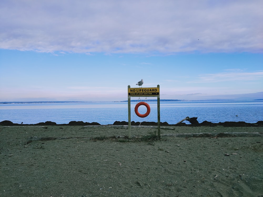 Señal de tráfico blanca y amarilla cerca del mar bajo el cielo azul durante el día