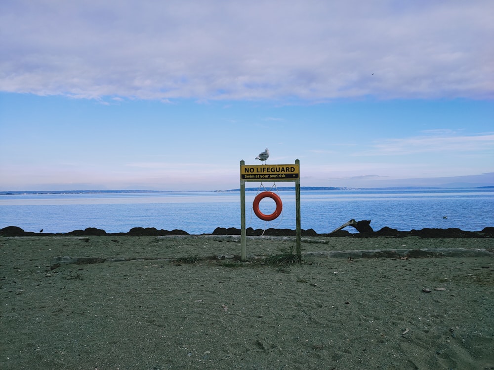 sinal de estrada branco e amarelo perto do mar sob o céu azul durante o dia