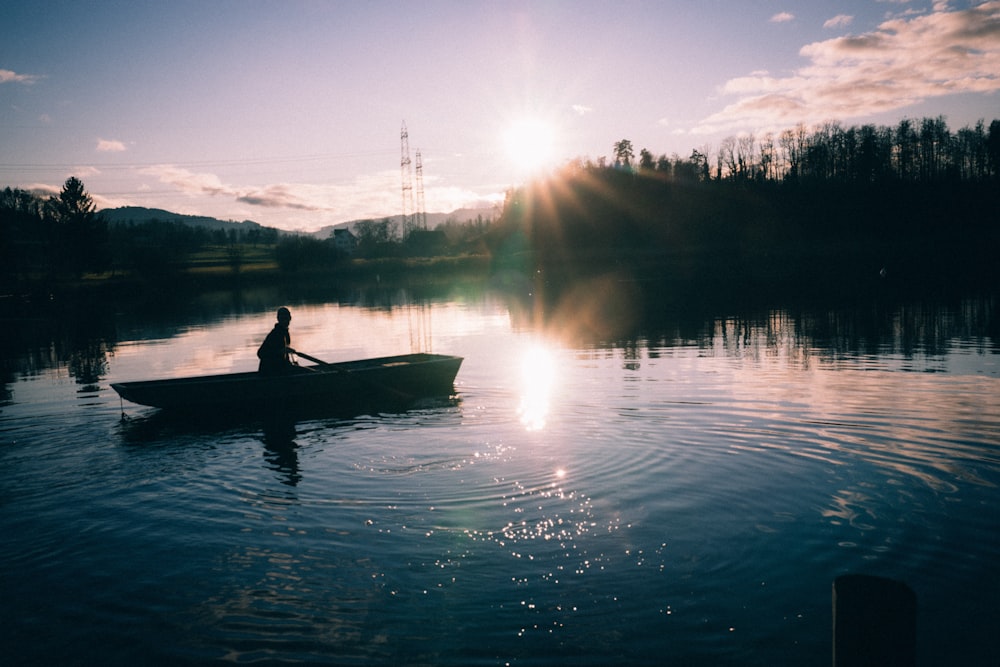 silhouette de personne chevauchant du canoë sur l’eau calme au coucher du soleil