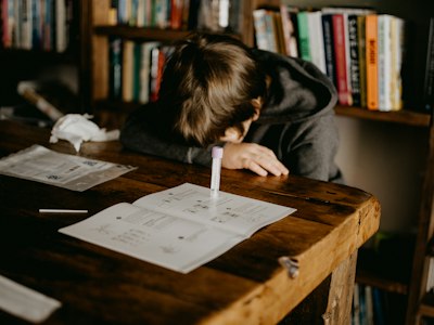 A teenage boy reading a book at a wooden table