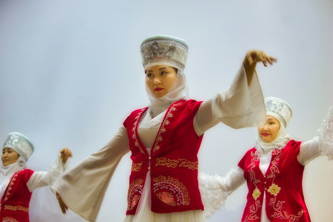 girl in red and white long sleeve dress, A Kyrgyz woman dressed in traditional garb dances with an ensamble.