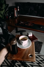 A sleek, modern workspace with a laptop, notebook, and a red coffee mug on a black desk.