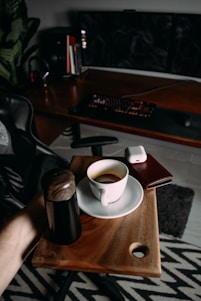 A sleek, modern workspace with automotive posters, a laptop showing influencer profiles, and a cup of coffee on a charcoal black desk.