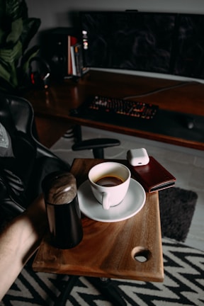 A standing desk converter on a modern workspace, holding a laptop and a cup of coffee.