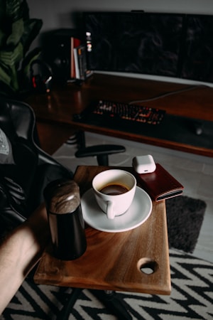 A modern workspace with a laptop, smartphone, and coffee cup on a dark wooden desk.