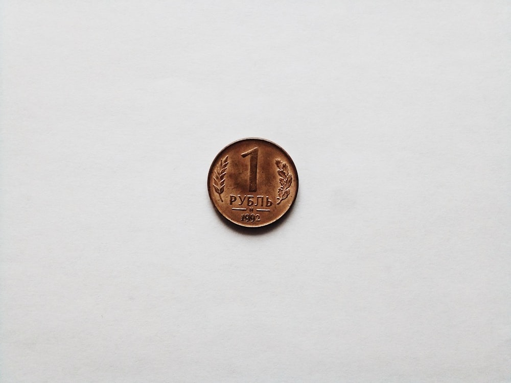 gold round coin on white surface