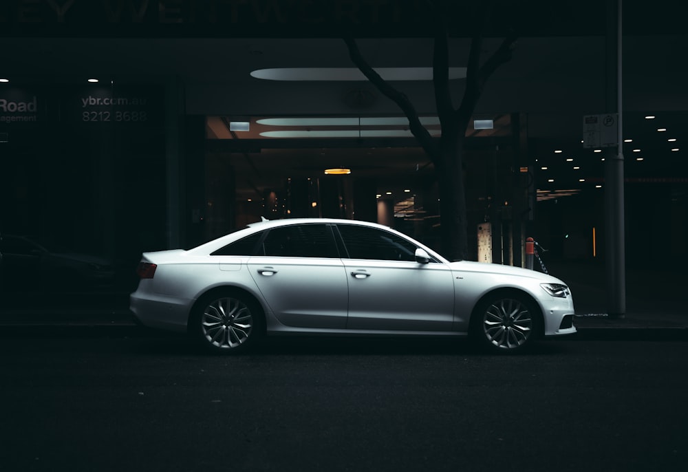 silver sedan parked on sidewalk during night time