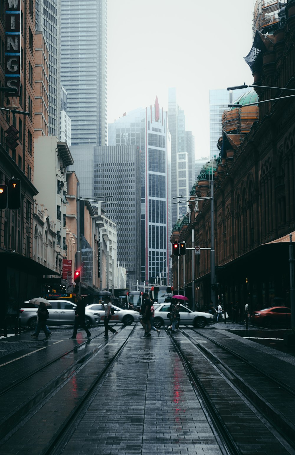 cars on road between high rise buildings during daytime