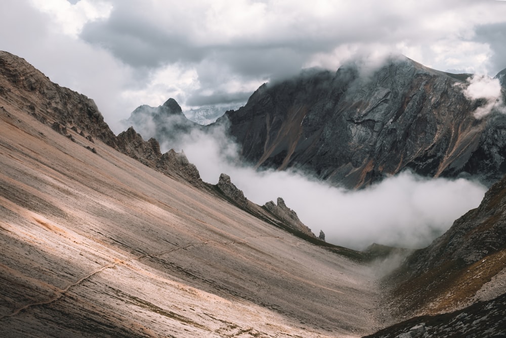 Montañas marrones y grises bajo nubes blancas durante el día