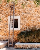white wooden ladder leaning on brown brick wall