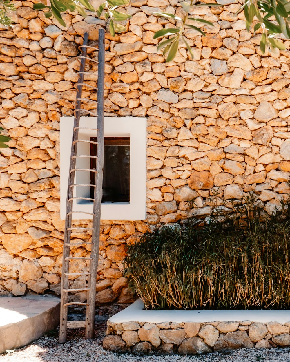 white wooden ladder leaning on brown brick wall