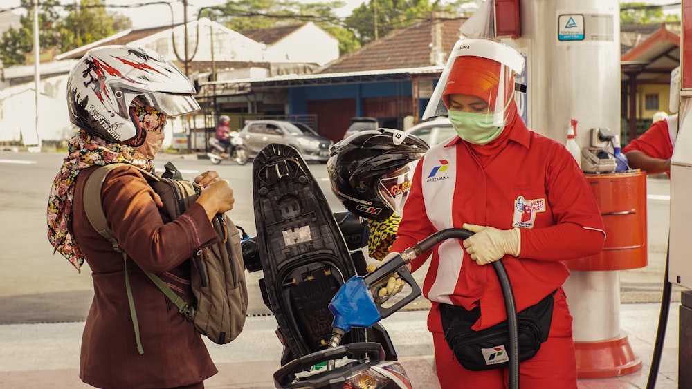 woman in green jacket and red hijab standing beside man in red jacket