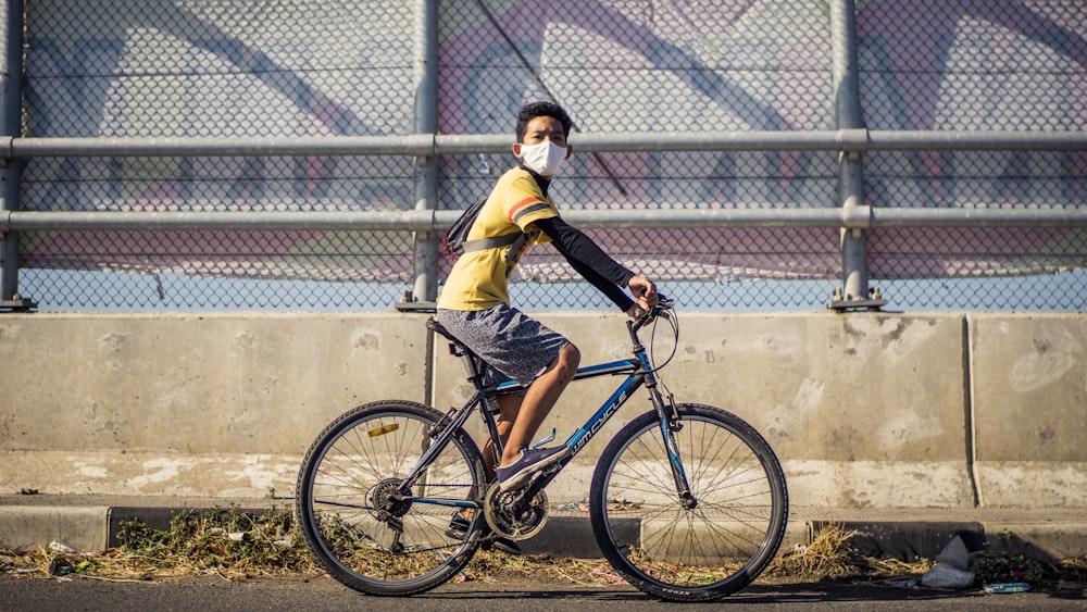 boy in yellow and black long sleeve shirt riding on bicycle