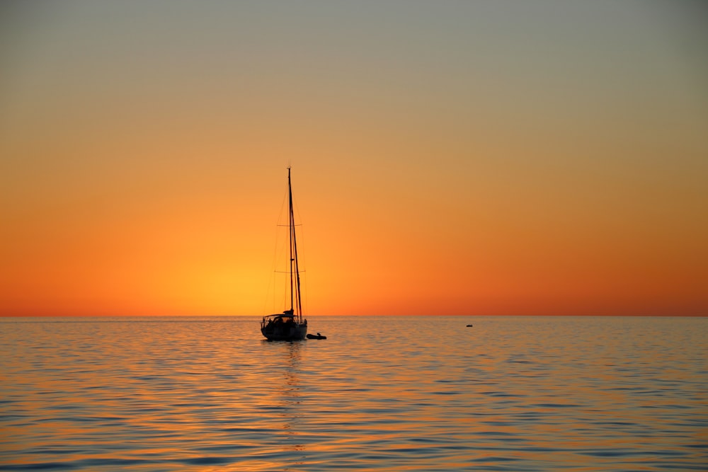 夕暮れ時の海上のボートのシルエット